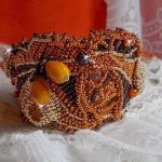 Bracelet Lady in Orange manchette Haute Couture brodé sur cuir avec cabochons en cristal, facettes, gouttes, perles nacrées, rocailles aux couleurs Orange, Jaune, Or, Marron pour un style contemporain